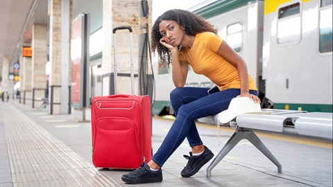 femme assise avec une valise dans une gare